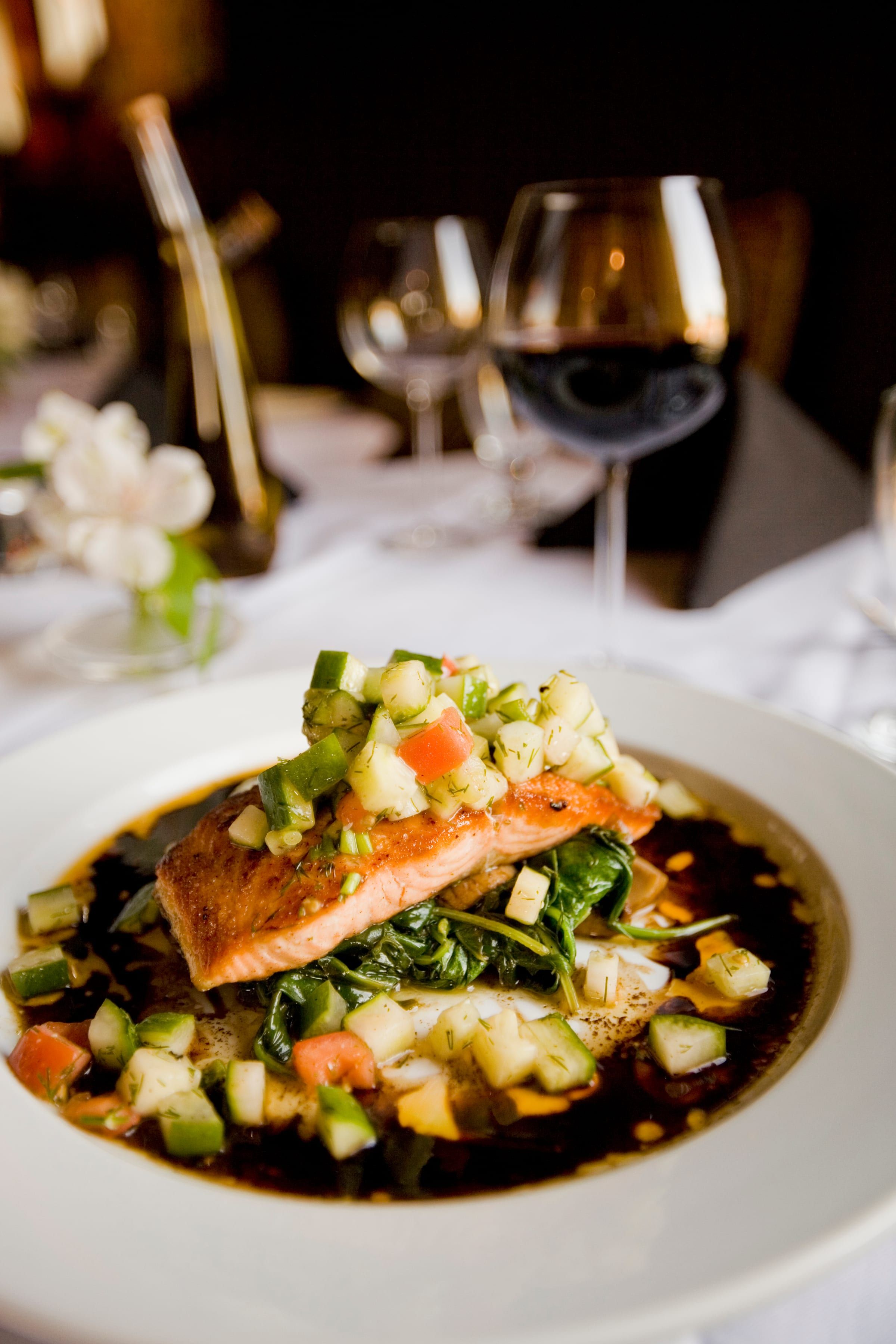 Seared salmon under a bright vegetable relish in a shallow bowl