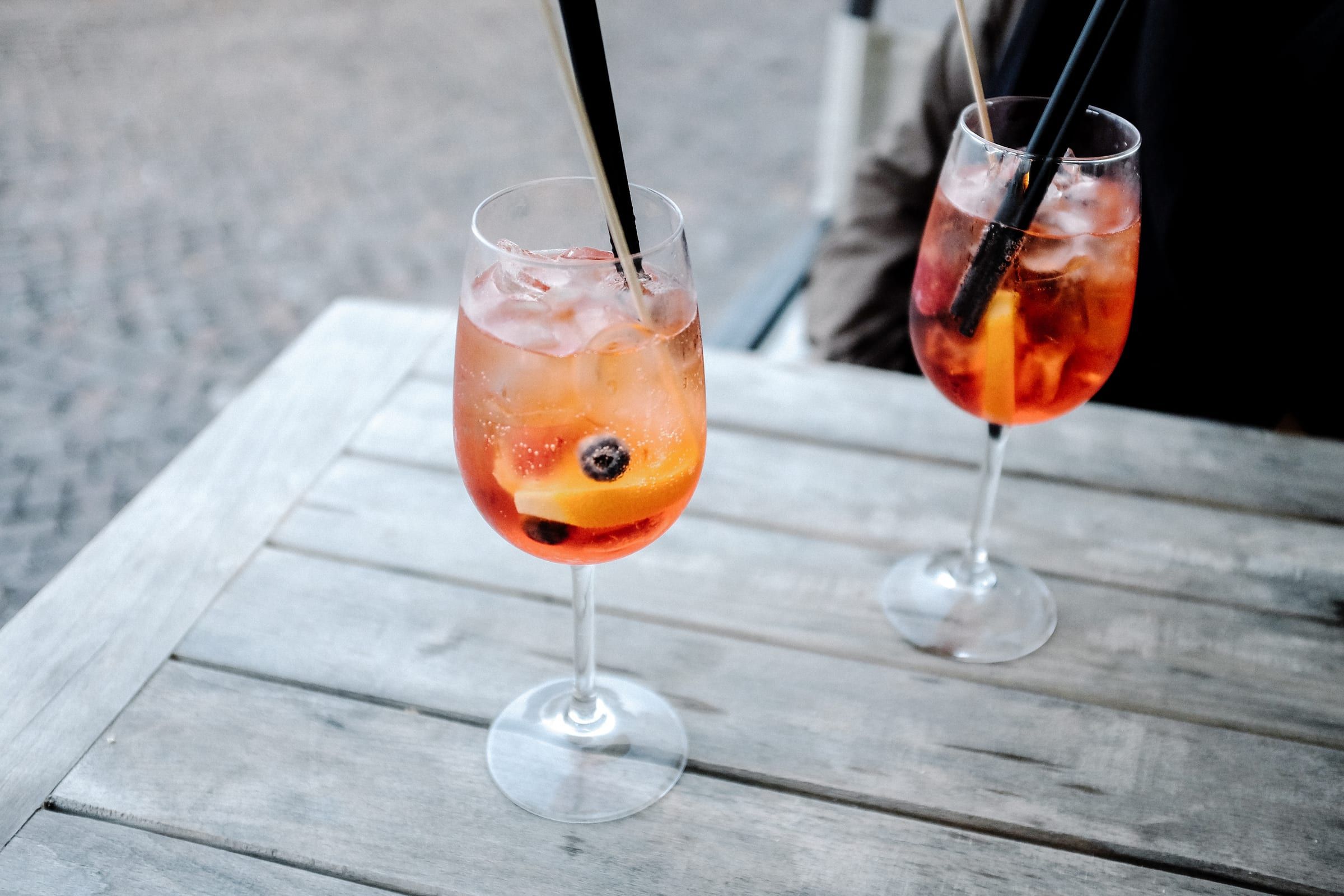 Two spritzes with straws on a weathered table outside